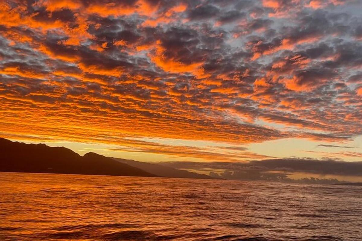 Una puesta de sol sobre un cuerpo de agua con nubes.