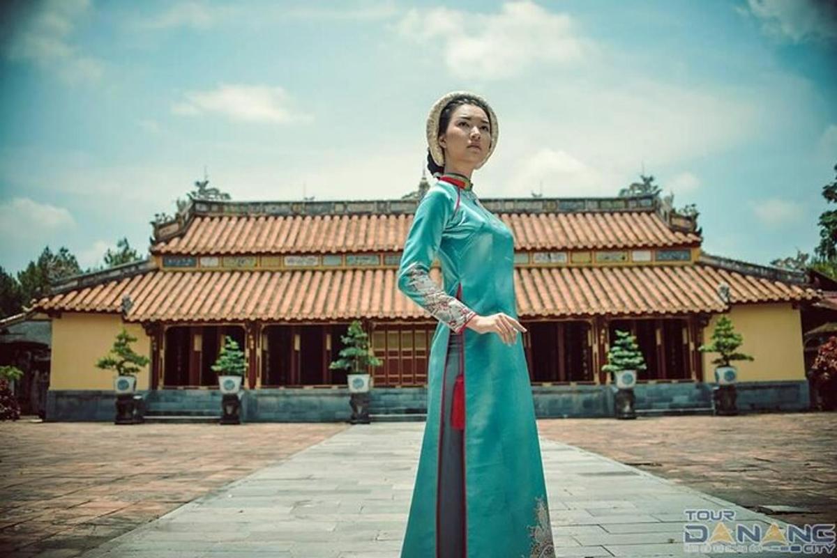 一位身穿绿色连衣裙的女子站在一栋建筑前