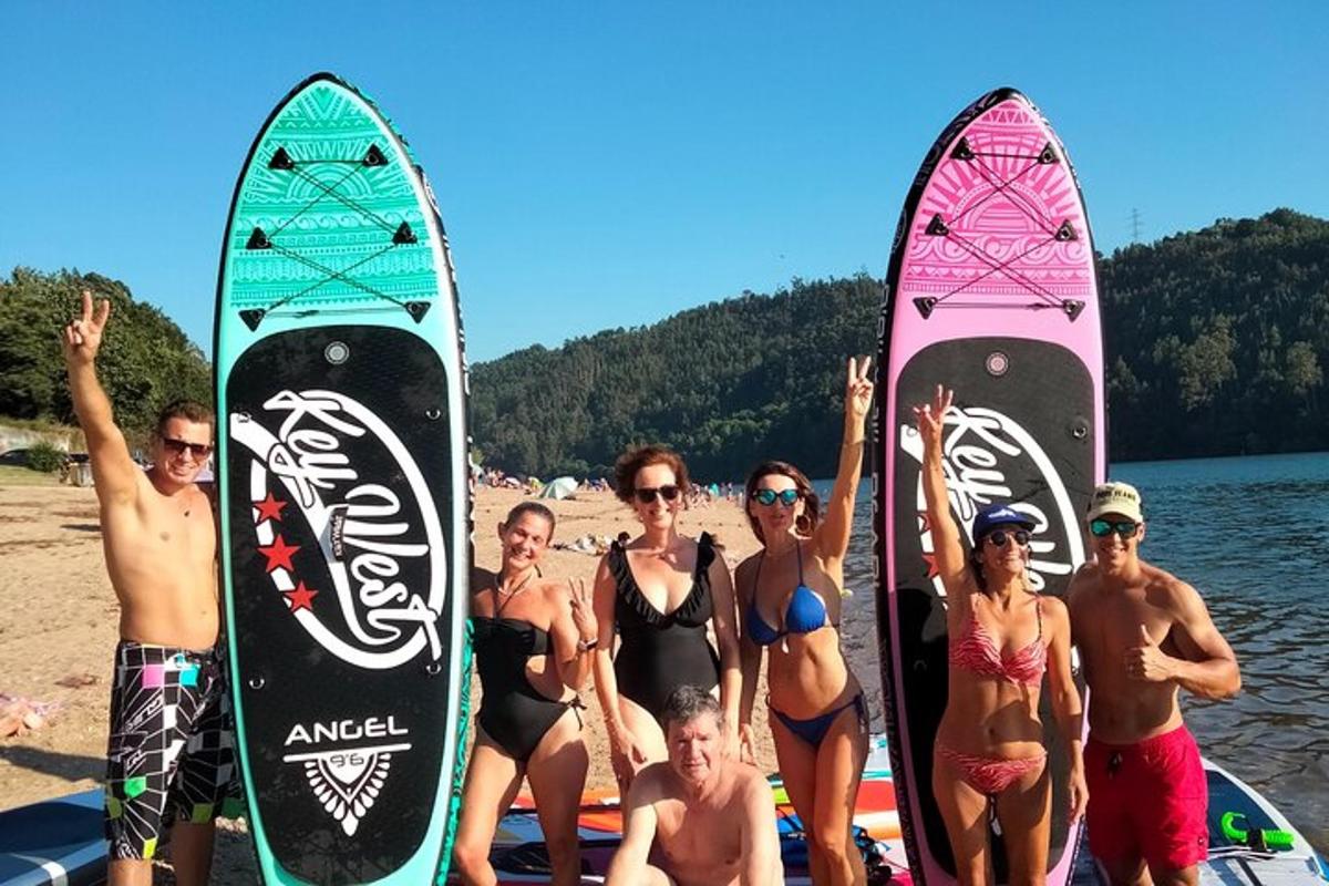 un grup de persones dempeus a la platja amb les seves taules de surf