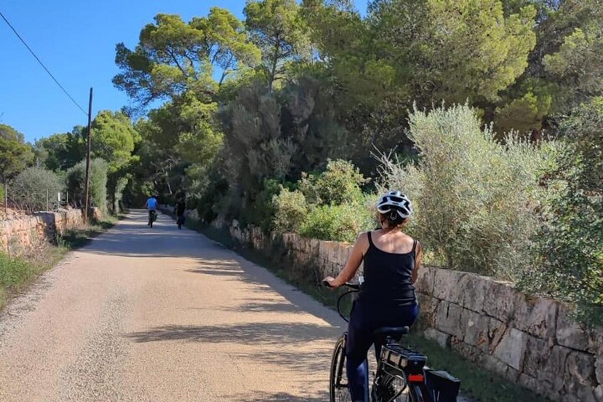 a woman riding a bike down a dirt road