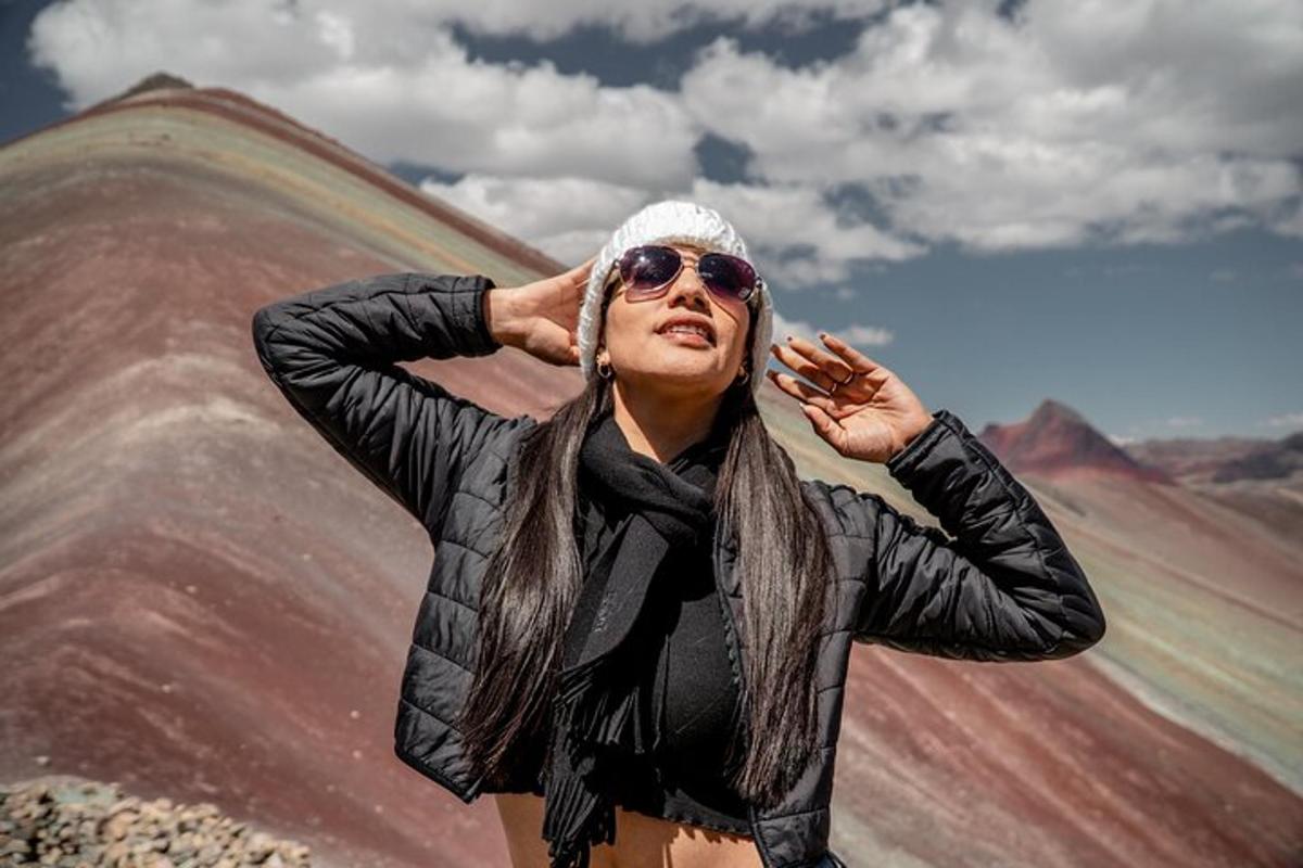 una donna che indossa occhiali da sole e una giacca in piedi su una montagna