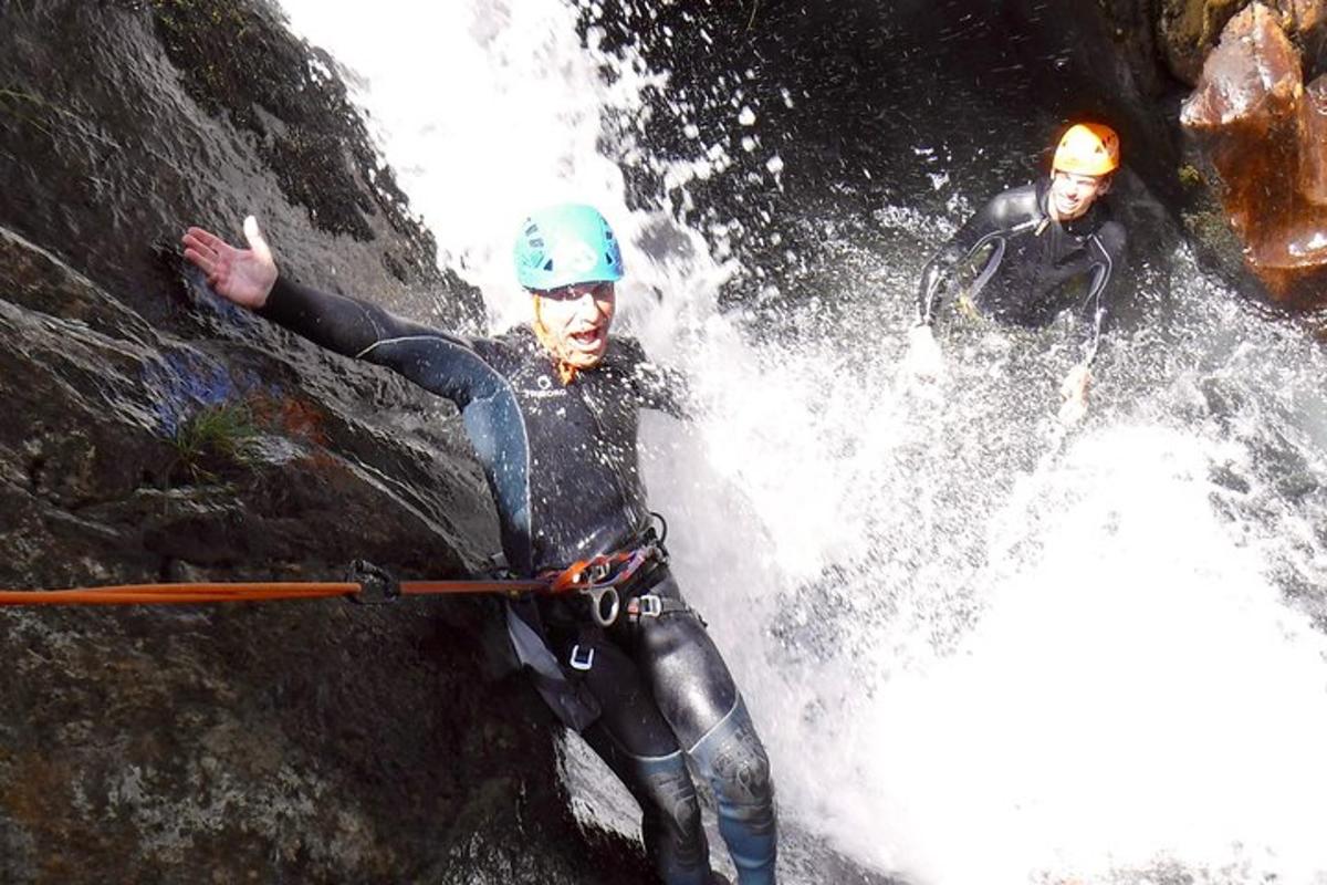 dois homens estão escalando uma cachoeira