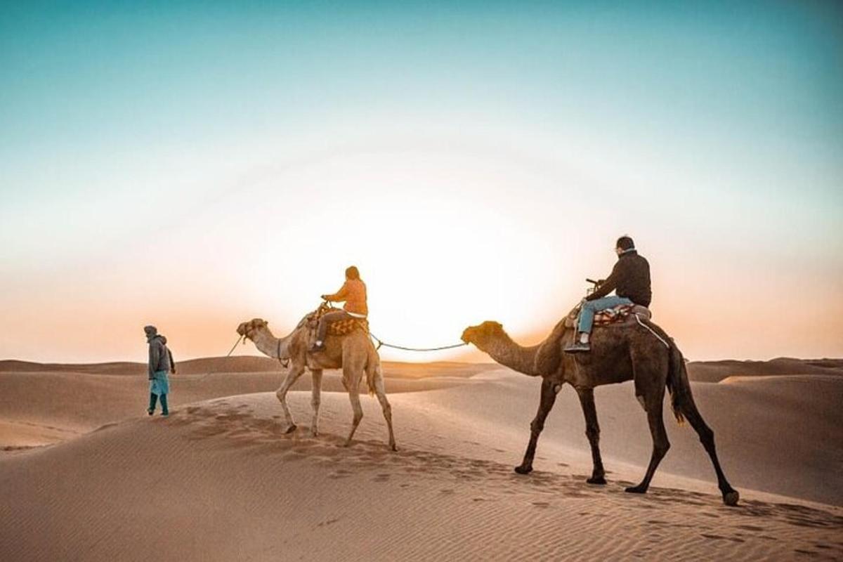 three people riding on camels in the desert