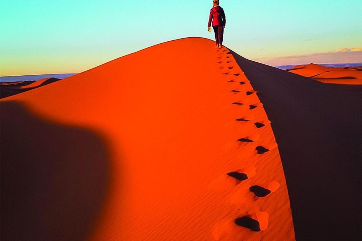 a man standing on top of a desert mound