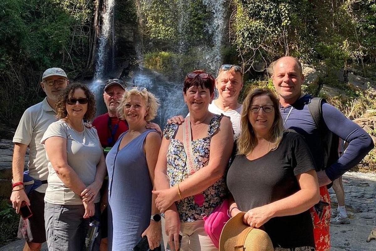 um grupo de pessoas em pé em frente a uma cachoeira
