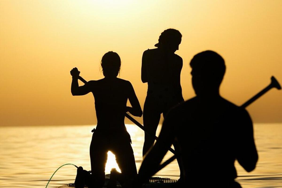Un grupo de personas de pie sobre una tabla de remo en el agua.