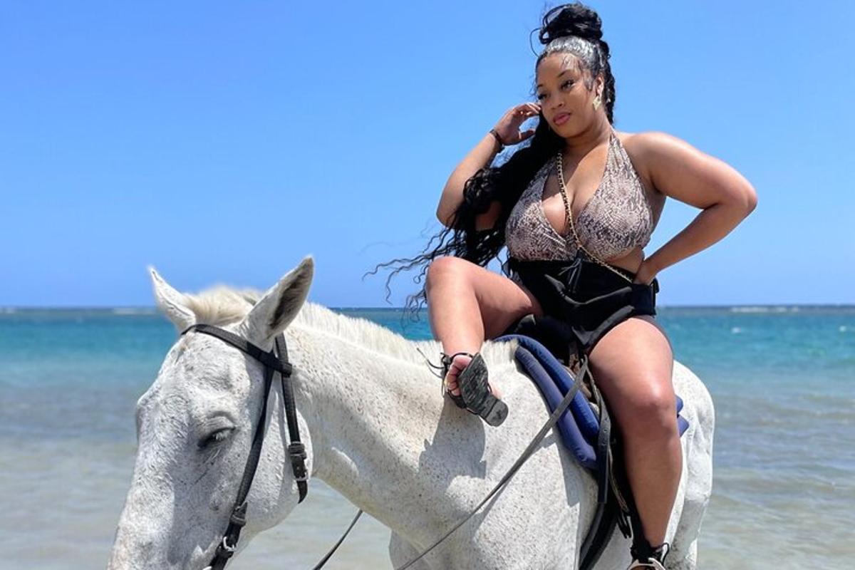 seorang wanita menunggang kuda di pantai sambil bercakap di telefon bimbit