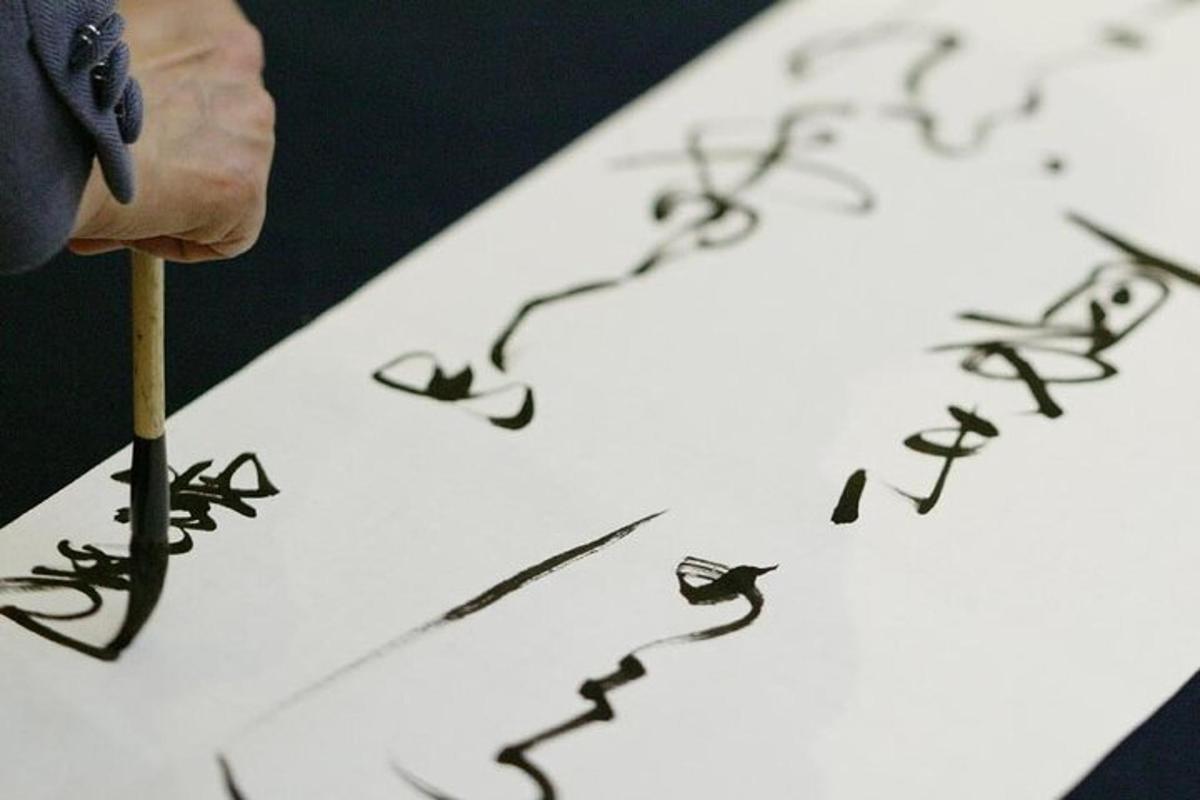 a person holding a pencil writingletters on a piece of paper