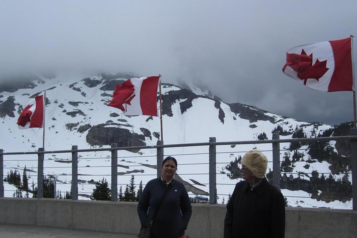 two people standing in front of a mountain with canadian flags