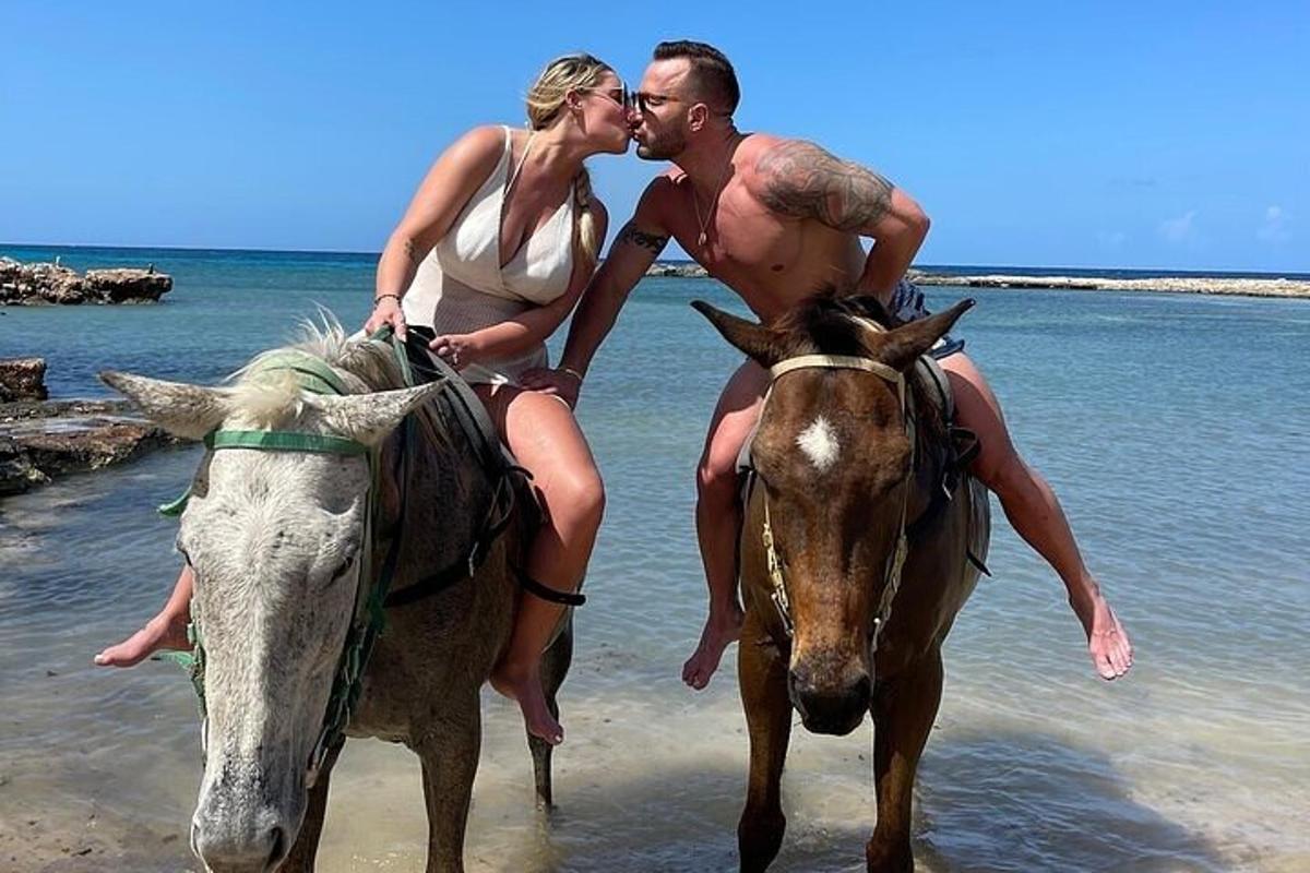 seorang pria dan seorang wanita menunggang kuda di pantai