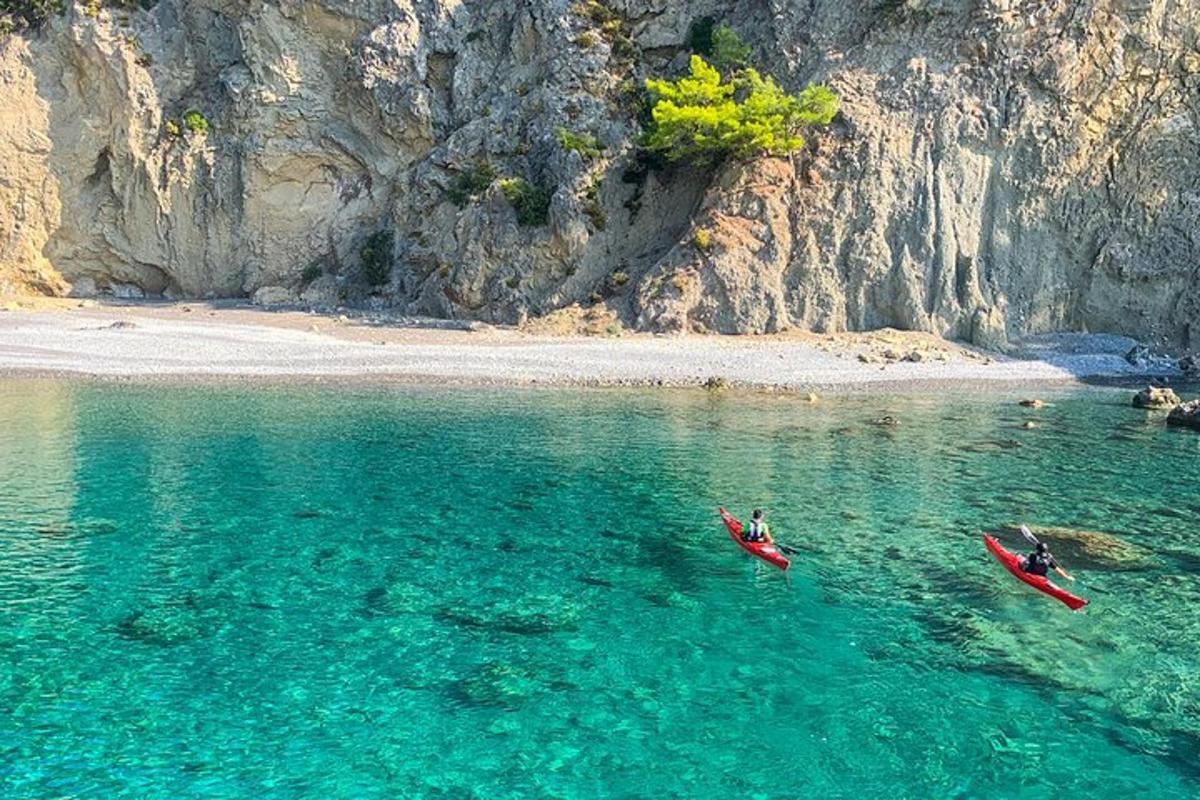 dve osebi v kajakih v vodi blizu plaže