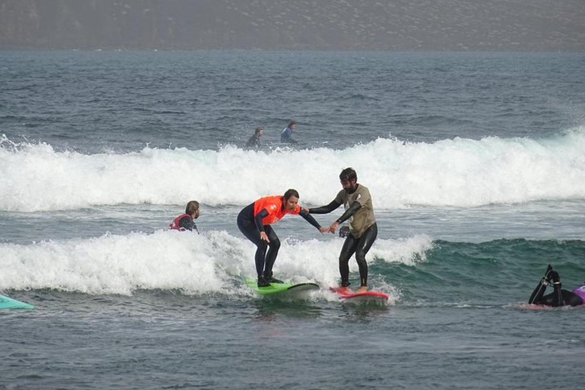 dues persones cavalcant una onada sobre taules de surf a l'oceà