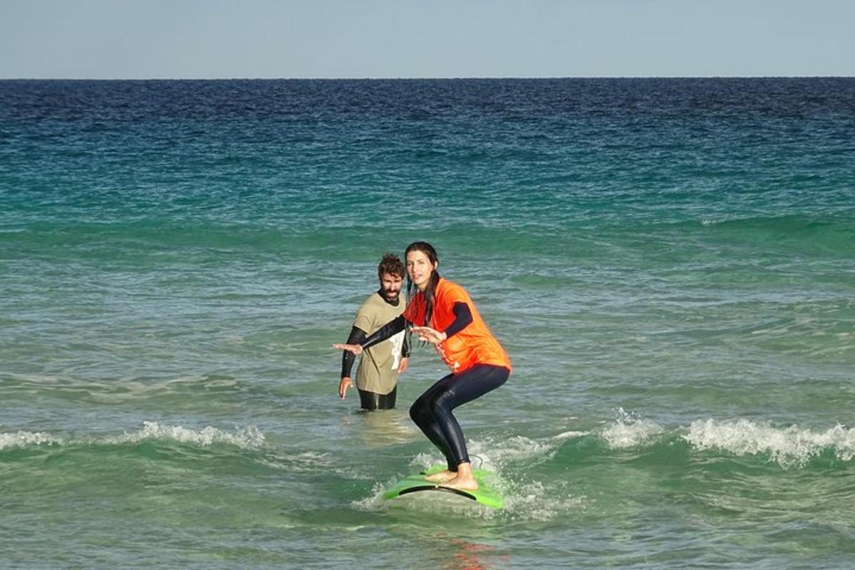 dues persones dempeus sobre una taula de surf a l'oceà