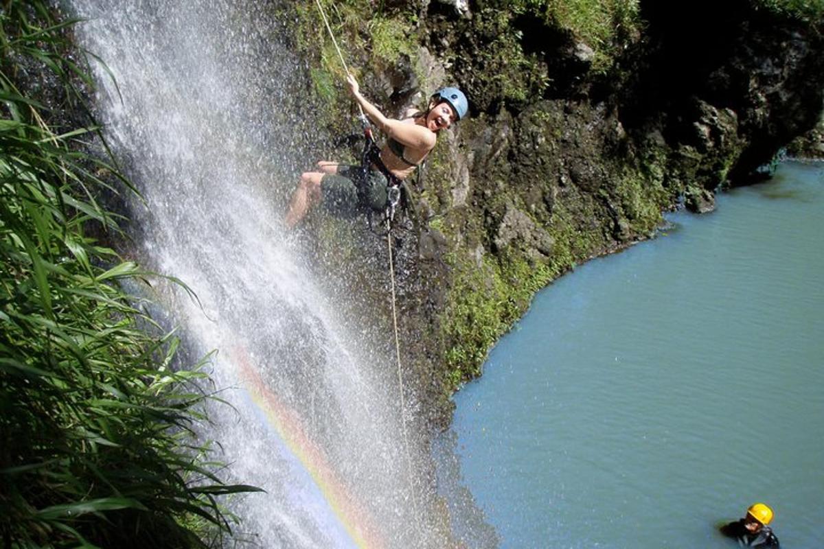 un uomo si sta calando in corda doppia da una cascata
