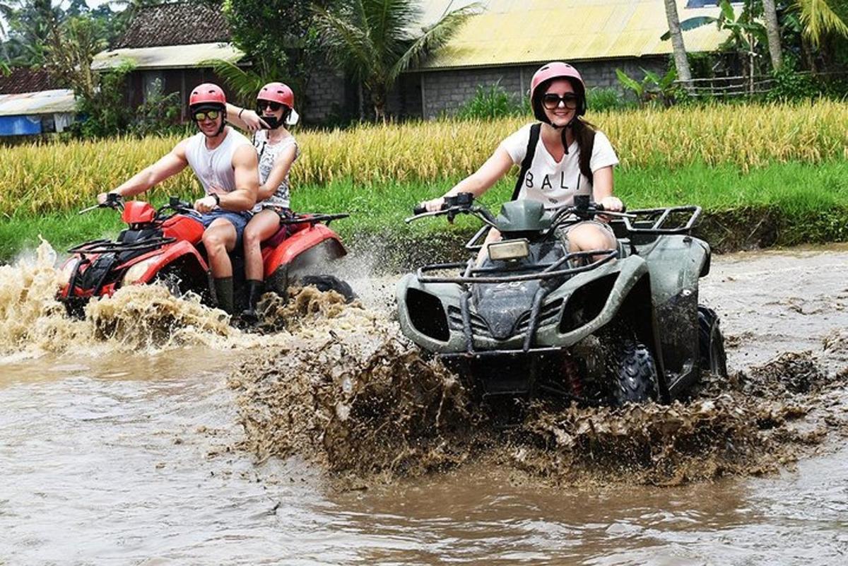 tre persone che guidano quad attraverso l'acqua