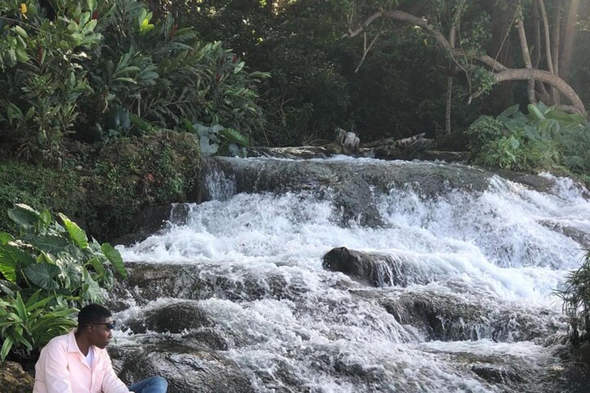 un home assegut en una roca al costat d'una cascada