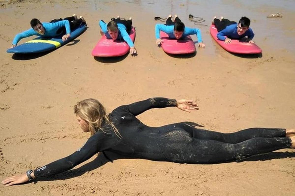 sekumpulan orang berbaring di atas papan luncur di pantai