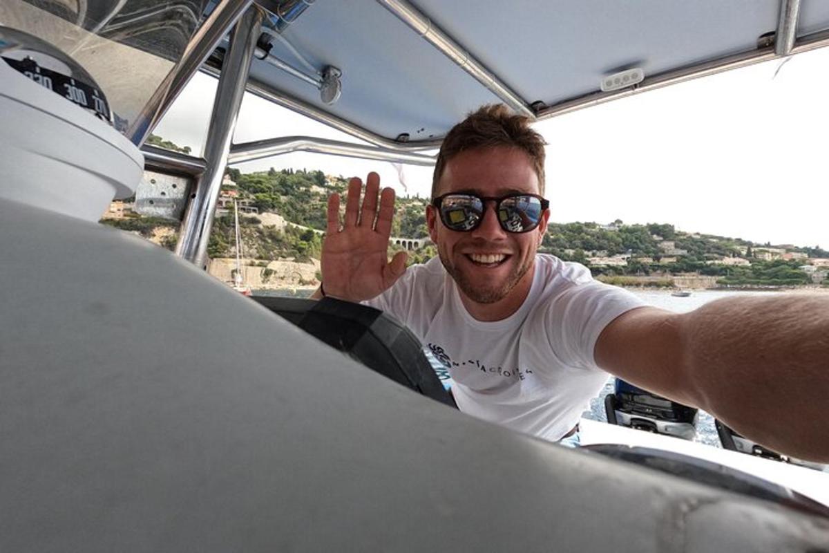 a man in sunglasses waving while sitting on a boat