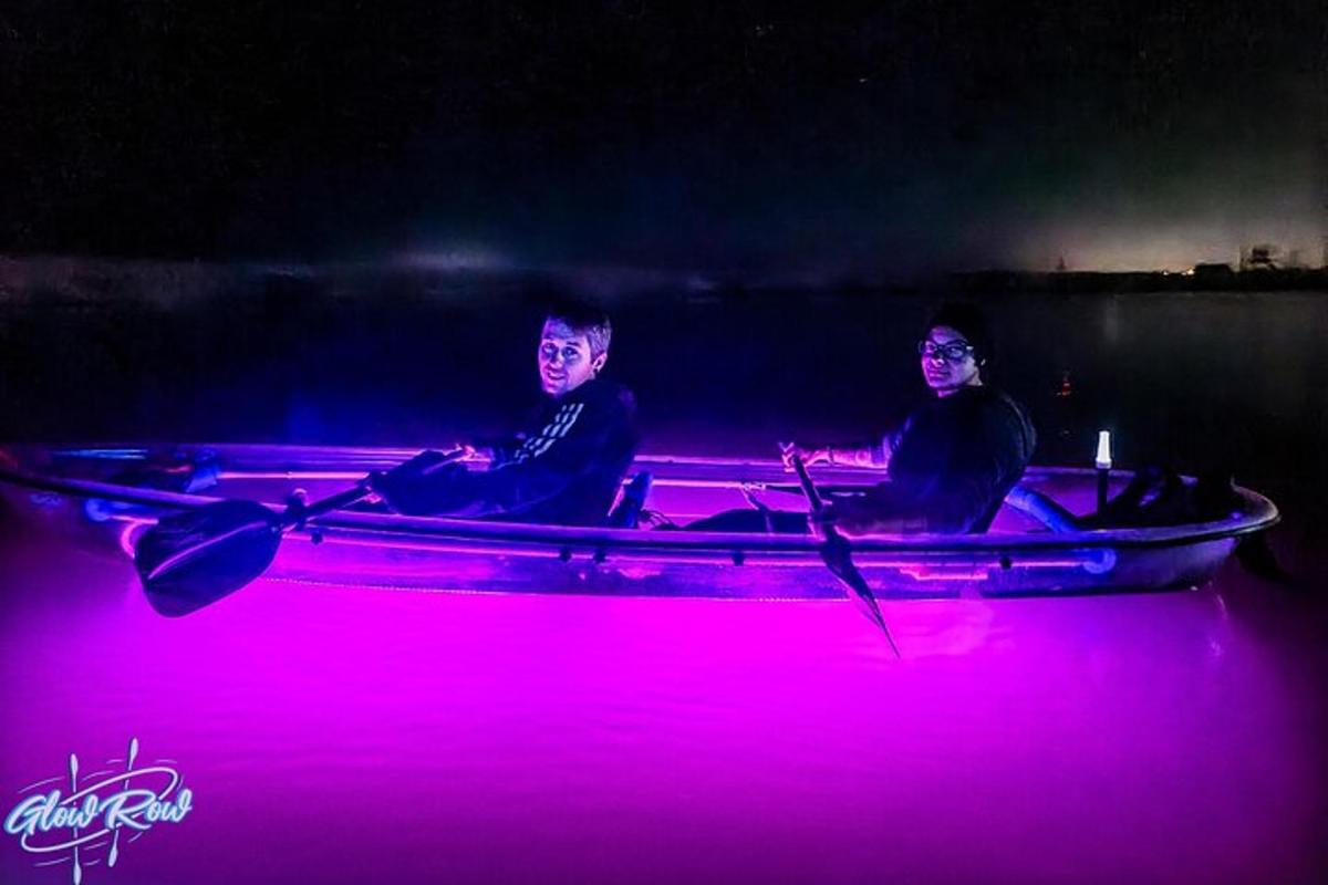 zwei Männer sitzen in einem Boot in einem rosa Licht