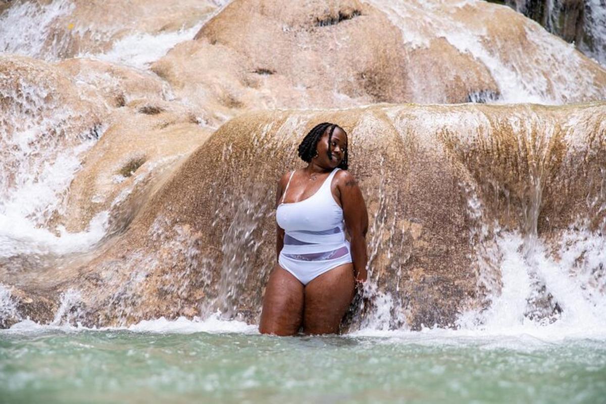 una donna in piedi nell'acqua di fronte a una cascata