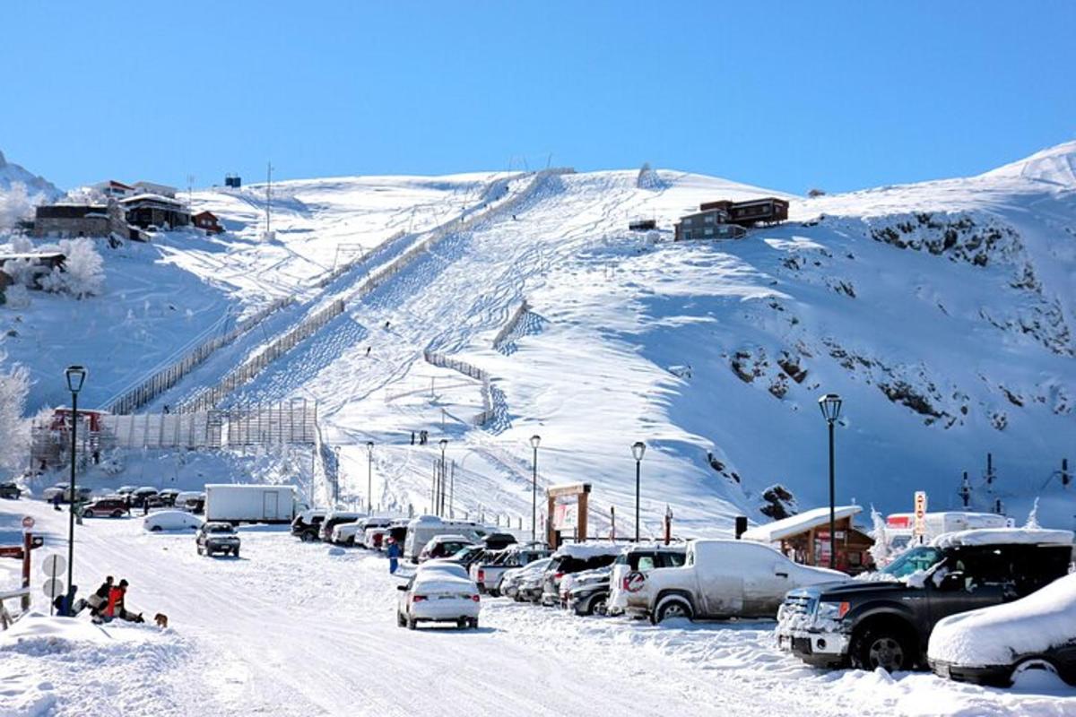 um estacionamento nevado com carros estacionados em uma montanha coberta de neve