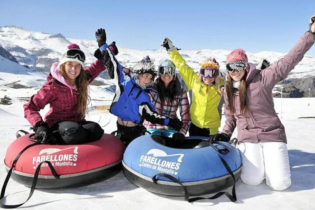 um grupo de pessoas sentadas em tubos de neve na neve