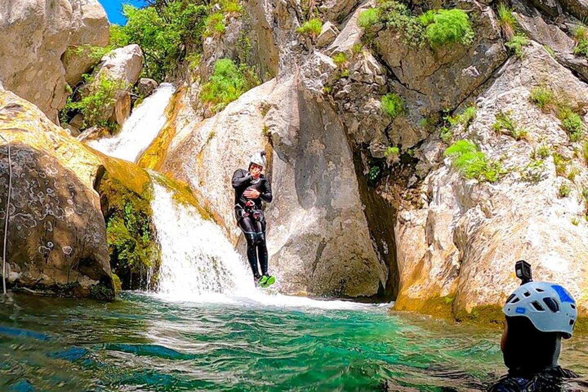 Dos personas de pie sobre una cascada en un río.