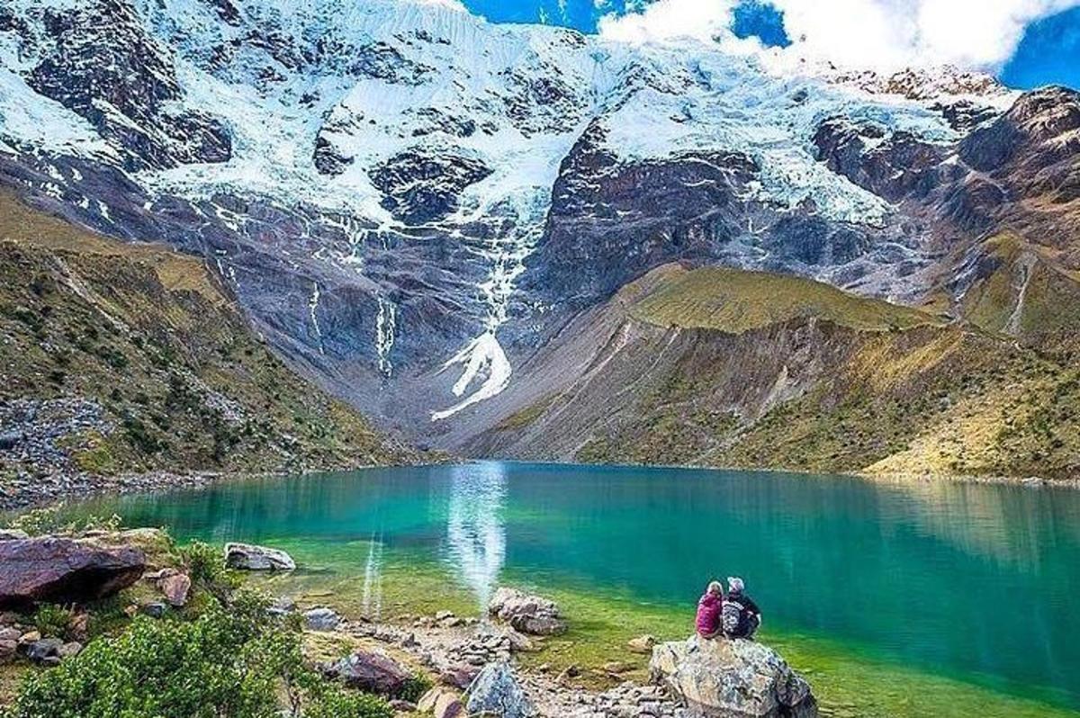 dues persones assegudes en una roca a prop d'un llac de muntanya