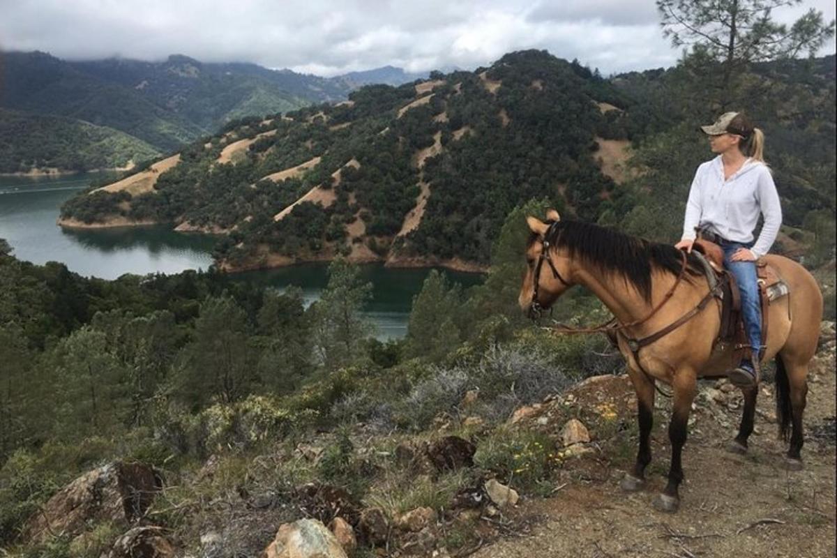 a woman riding a horse on top of a mountain