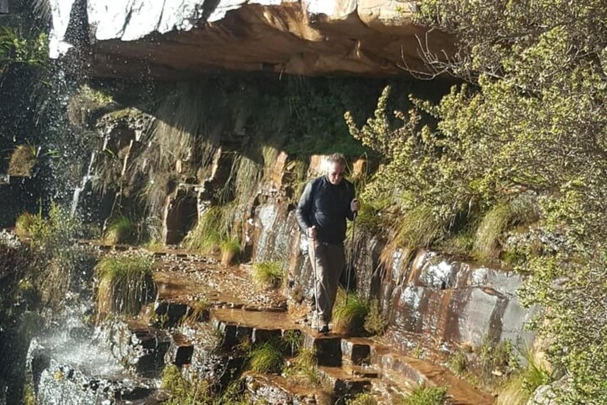 a man walking on a path in front of a waterfall