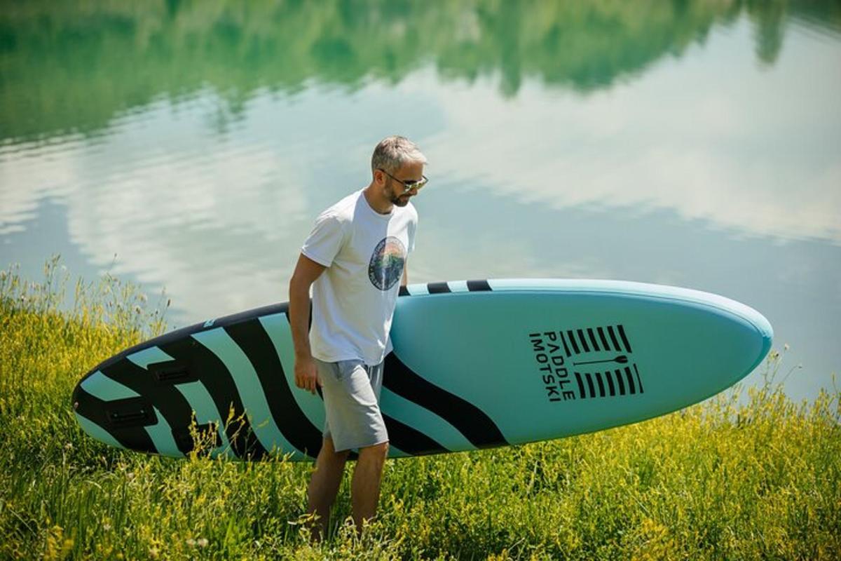 Un hombre parado en el césped con su tabla de surf.