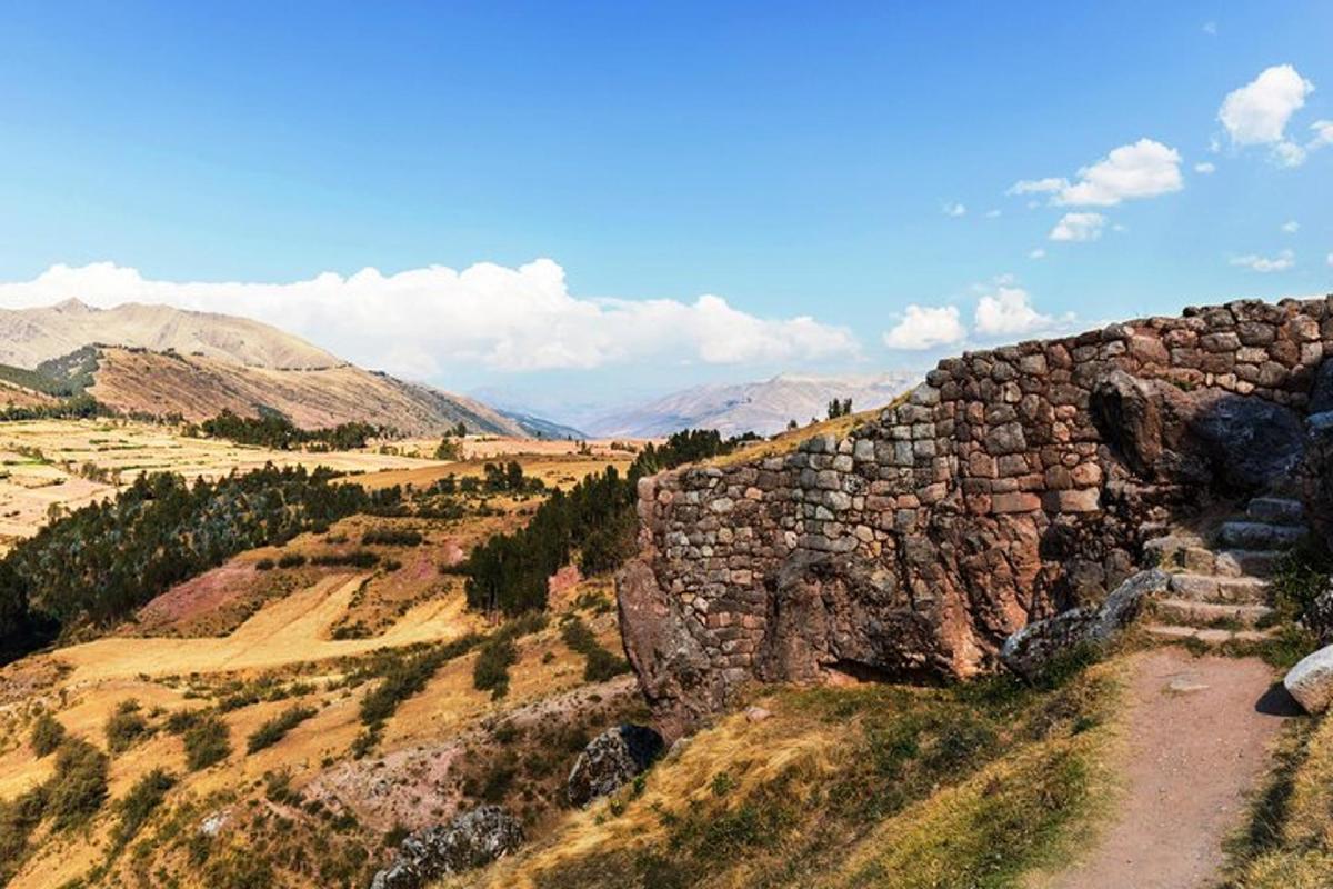 a stone wall on top of a field with mountains