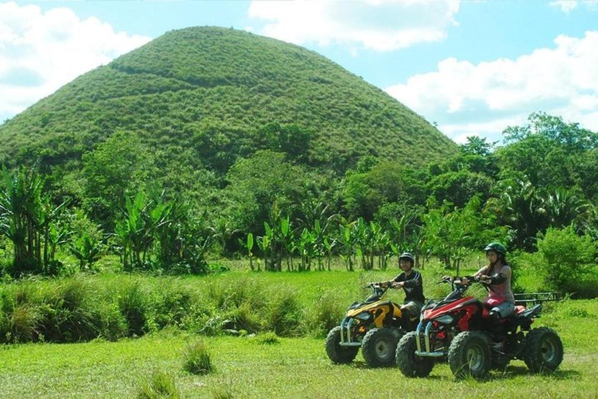 due persone in sella a un quad davanti a una grande collina