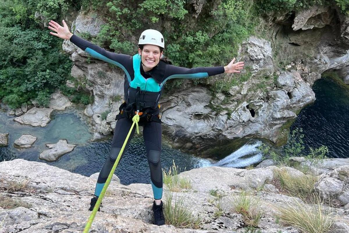 una dona jove amb un vestit de neoprè dempeus sobre una roca al costat d'un riu