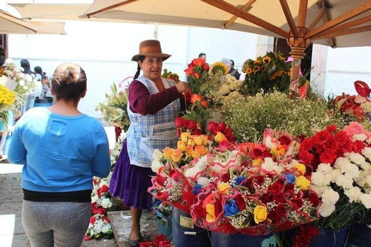 a man in a hat standing next to a display of flowers