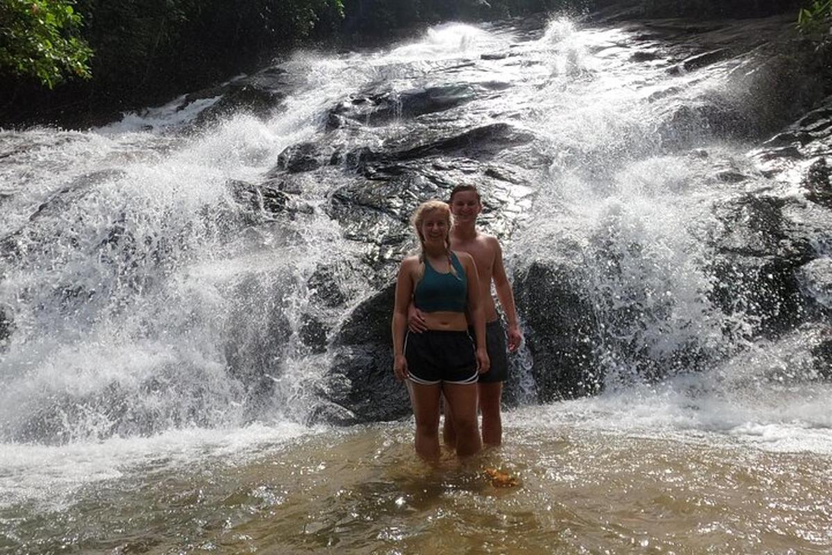 a man and a woman standing in front of a waterfall