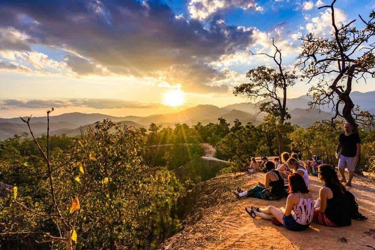 un gruppo di persone sedute su una collina a guardare il tramonto