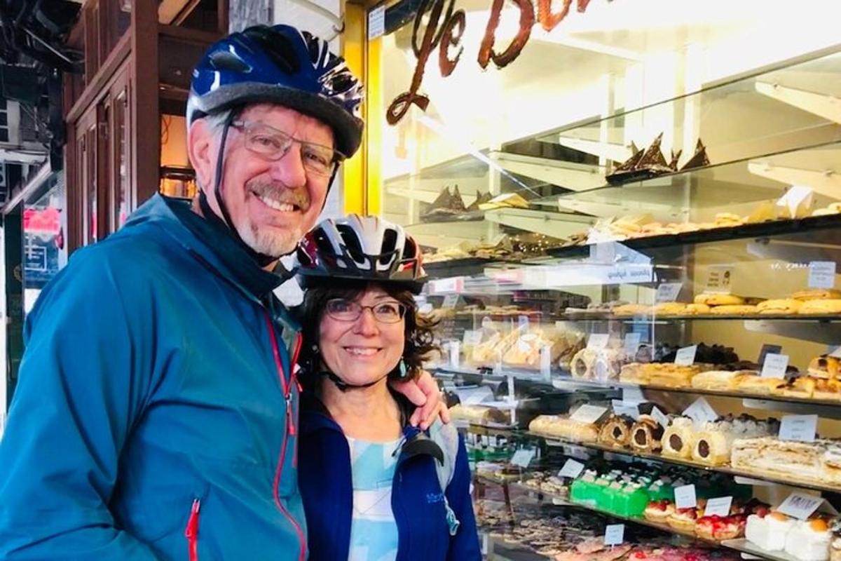 an older man and woman standing in front of a bakery