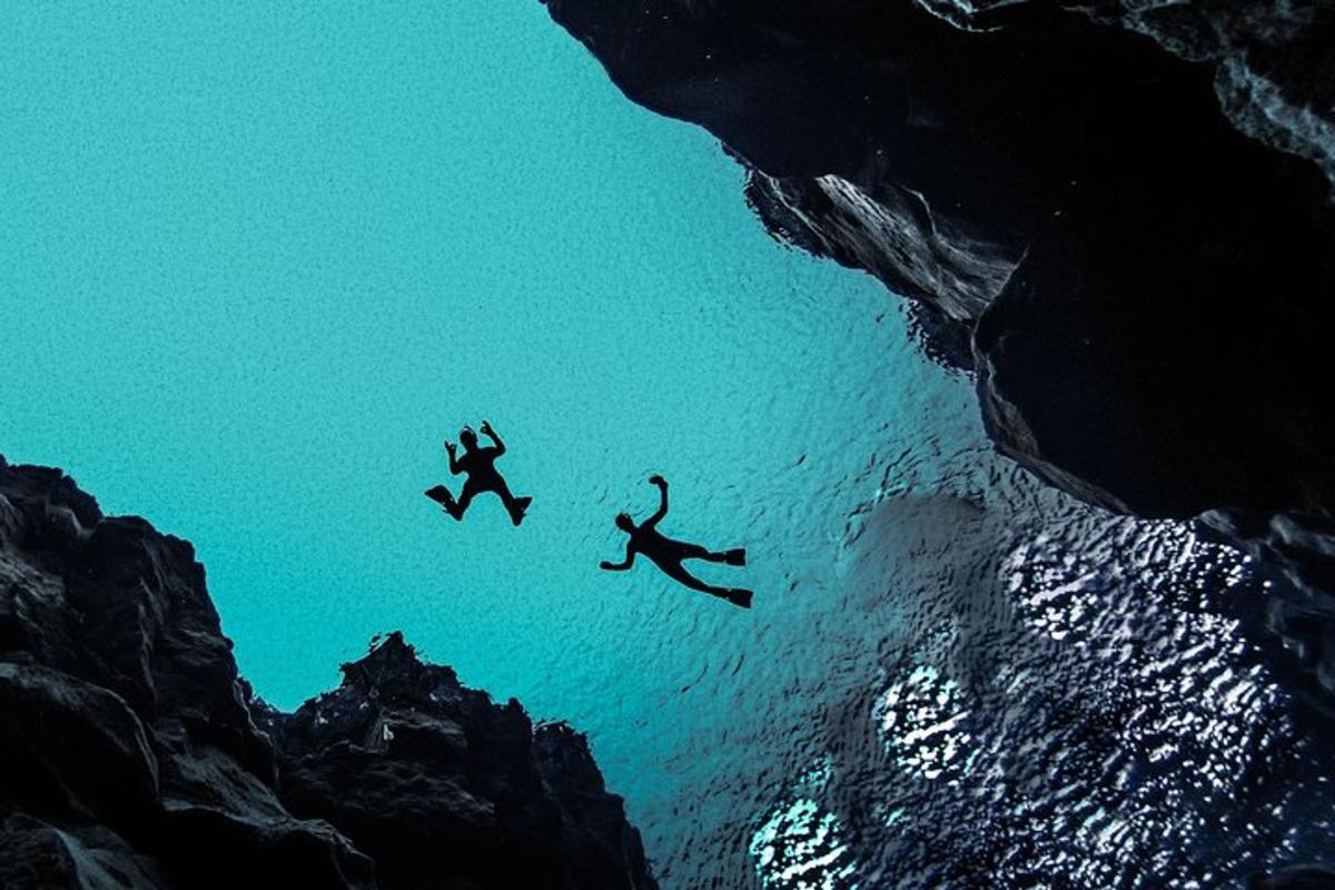 tre persone che saltano in acqua vicino all'oceano