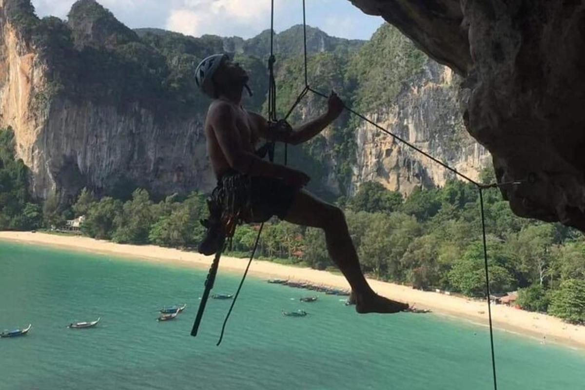 un uomo appeso a una corda da una scogliera sopra l'acqua