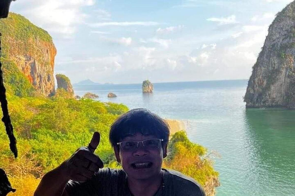 a man giving a thumbs up in front of the ocean