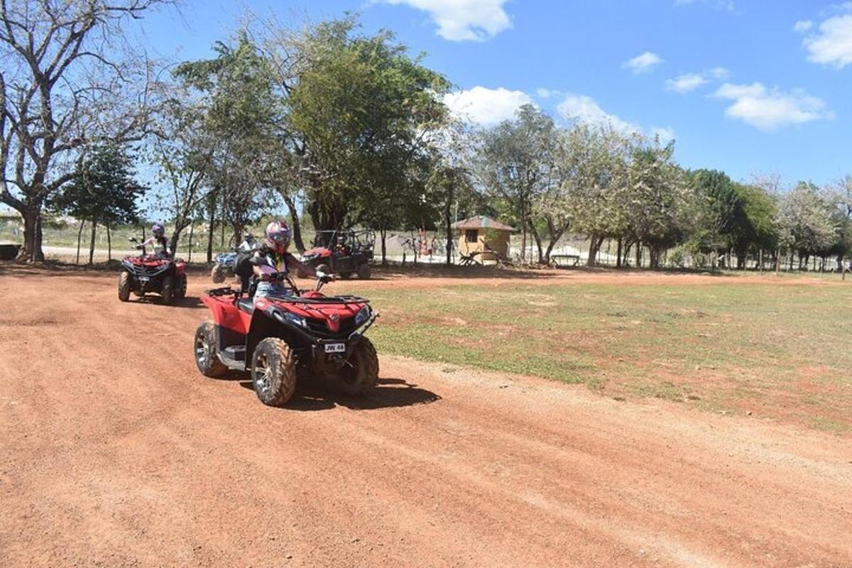 dues persones que condueixen quads per un camí de terra