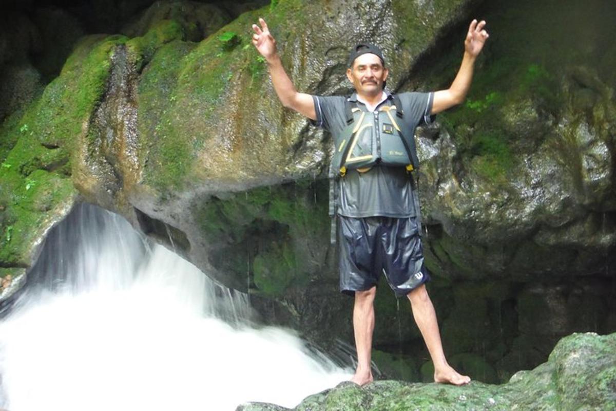 a man standing on a rock in front of a waterfall