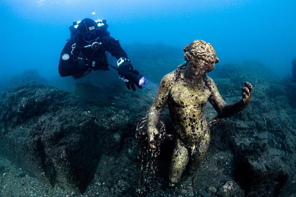 muž ve vodě se sochou v oceánu