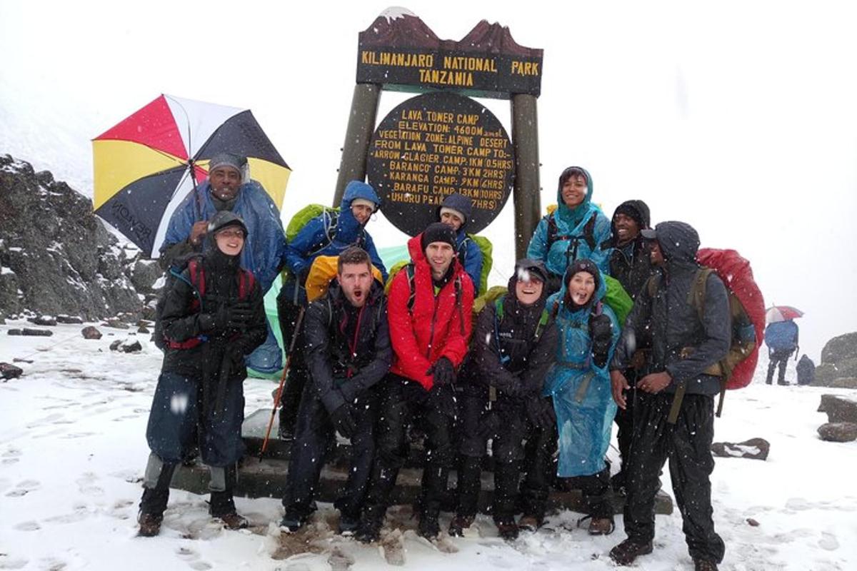 um grupo de pessoas posando em frente a uma placa na neve
