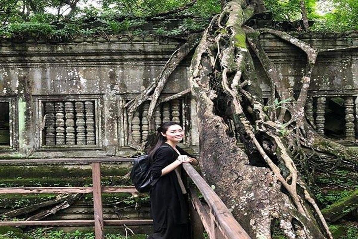 a woman in a black dress standing next to a tree