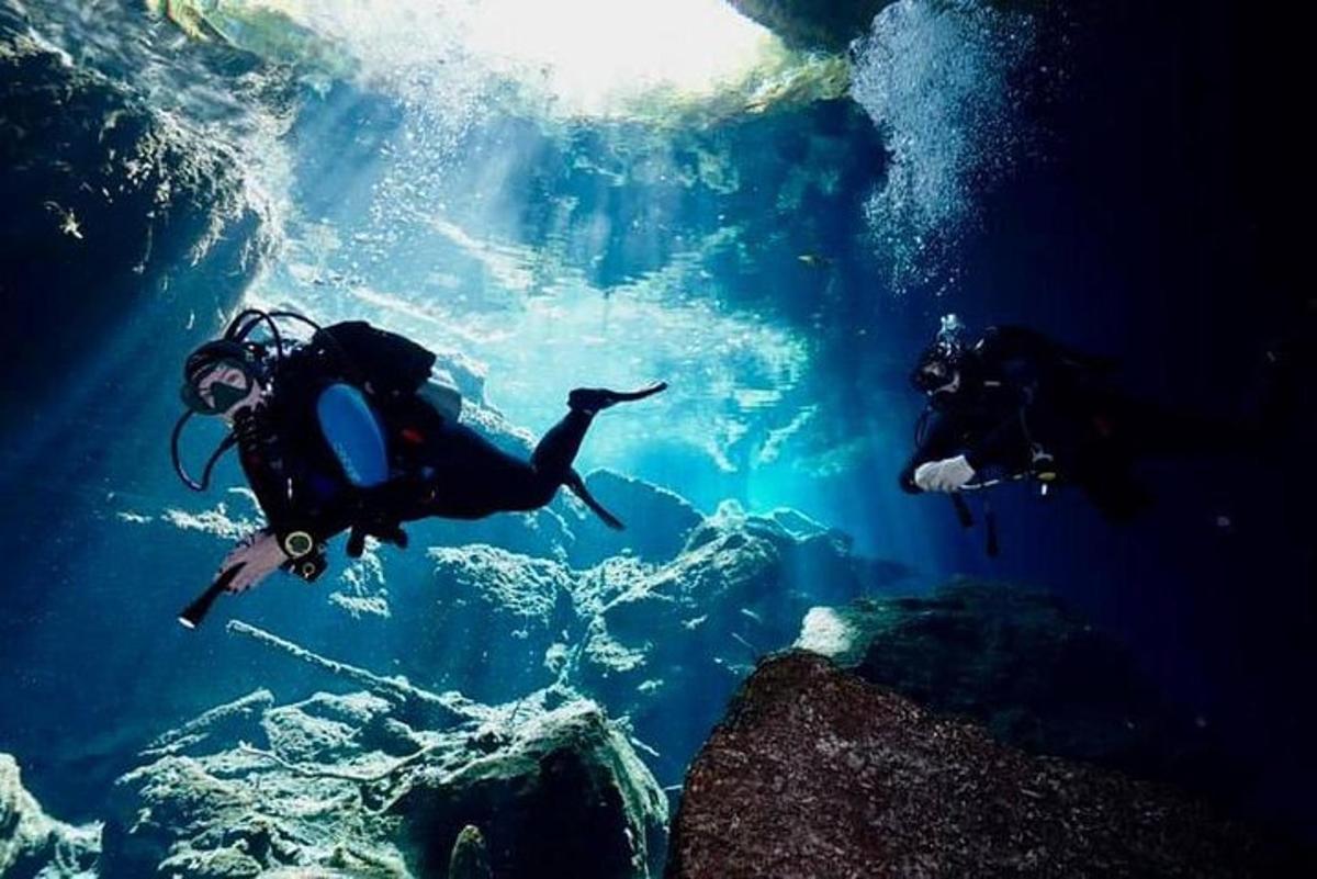 two people swimming in the water in a cave
