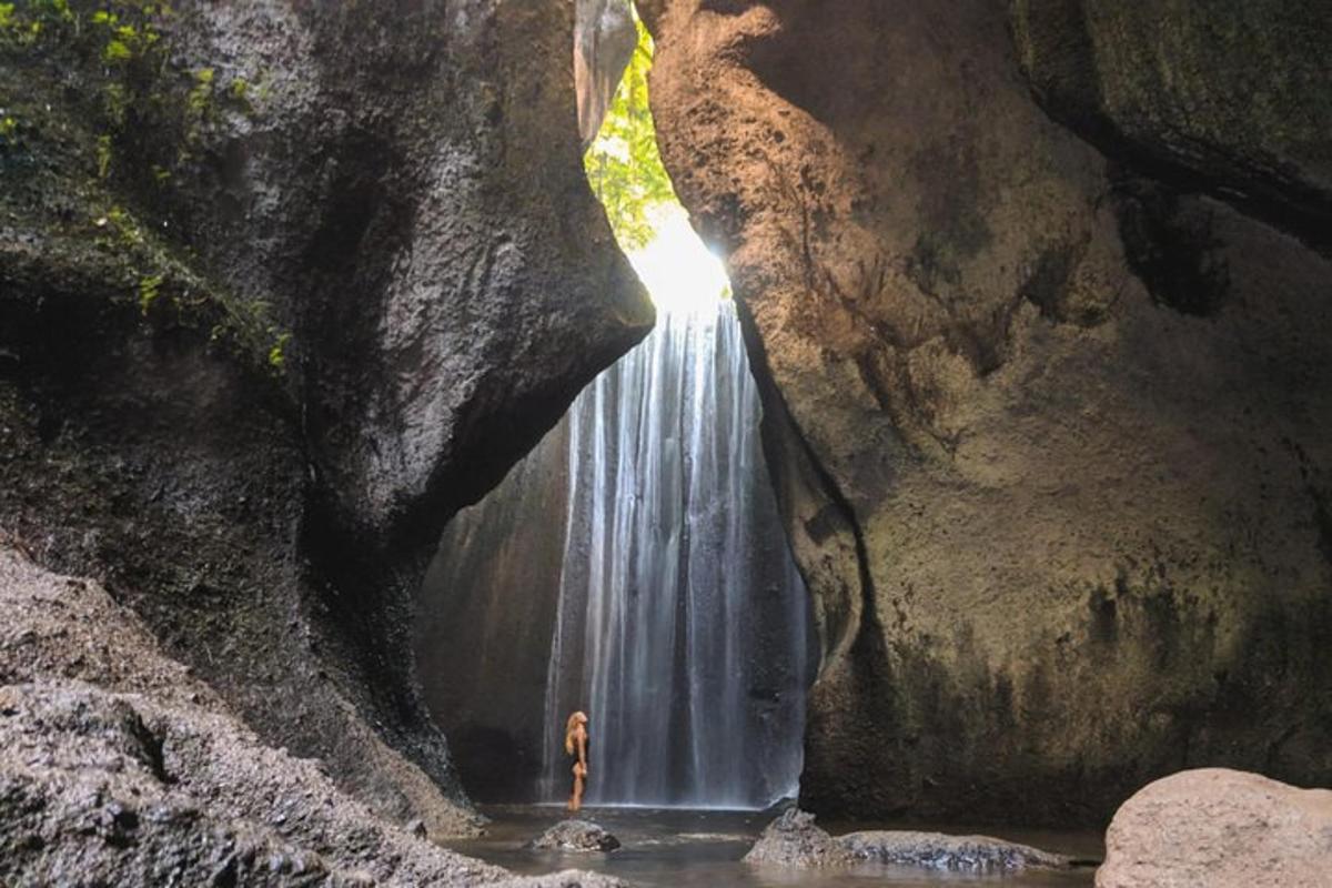 maður stendur fyrir framan foss í helli