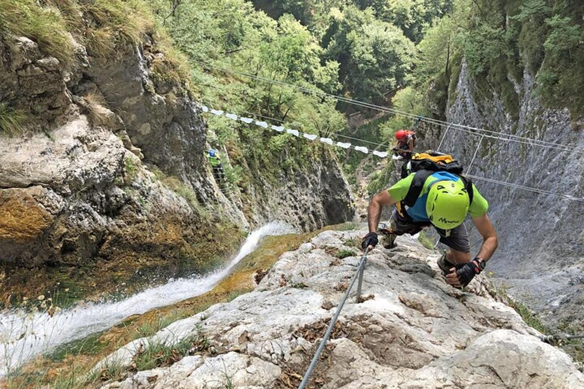 dva lidé kráčející po skále poblíž vodopádu