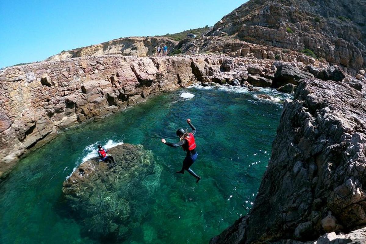 dues persones saltant d'una roca a una massa d'aigua